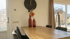 Ein Essbereich mit Holztisch, zwei Stühlen, einer Wanduhr und einer Blumenvase.