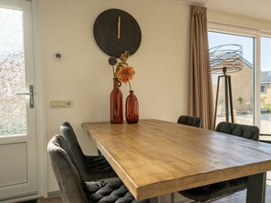 Ein Essbereich mit Holztisch, zwei Stühlen, einer Wanduhr und einer Blumenvase.