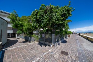 A paved walkway with a tree-lined path, a metal fence, and a building with a white facade. - A comfortable 49-square-meter apartment, perfect for five people, located on the third floor (Scala A) of a building with an elevator (NOT suitable for people with disabilities) directly facing the seafront.The property is located in Lignano Sabbiadoro i (Lignano Sabbiadoro)