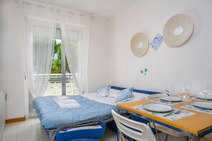 Ein Schlafzimmer mit einem Bett, einem Essplatz und einem Balkon mit Vorhängen.