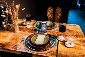 Ein Esszimmertisch gedeckt mit Tellern, Gläsern, Besteck und Dekoration.