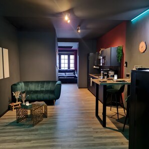 Un espacio moderno para vivir con sofá, mesa de comedor, zona de cocina y vistas al dormitorio.