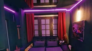 A modern bedroom with a bed, red curtains, and purple ambient lighting.