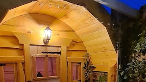 A wooden structure with a door, a light fixture, and a bench.