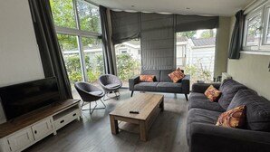 Una sala de estar moderna con un sofá, sillones, una mesa de centro y un televisor.