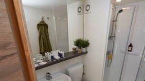 A bathroom with a sink, toilet, shower, and a mirror. - Glamping Tent Luxe 4 (Kaatsheuvel)