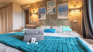 Een hotelkamer met een groot bed, een blauwe deken en drie ingelijste posters aan de muur.