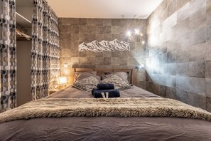 Un dormitorio moderno con una cama grande, cortinas estampadas, un cuadro de montañas y un ambiente acogedor.