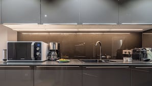 Een moderne keuken met roestvrijstalen apparatuur, een koffiezetapparaat en een spoelbak.