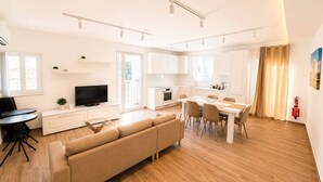 Un salon moderne avec un canapé, un téléviseur et un coin repas.