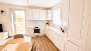 Une cuisine moderne avec des meubles blancs, un four encastré et un coin repas comprenant une table et des chaises.