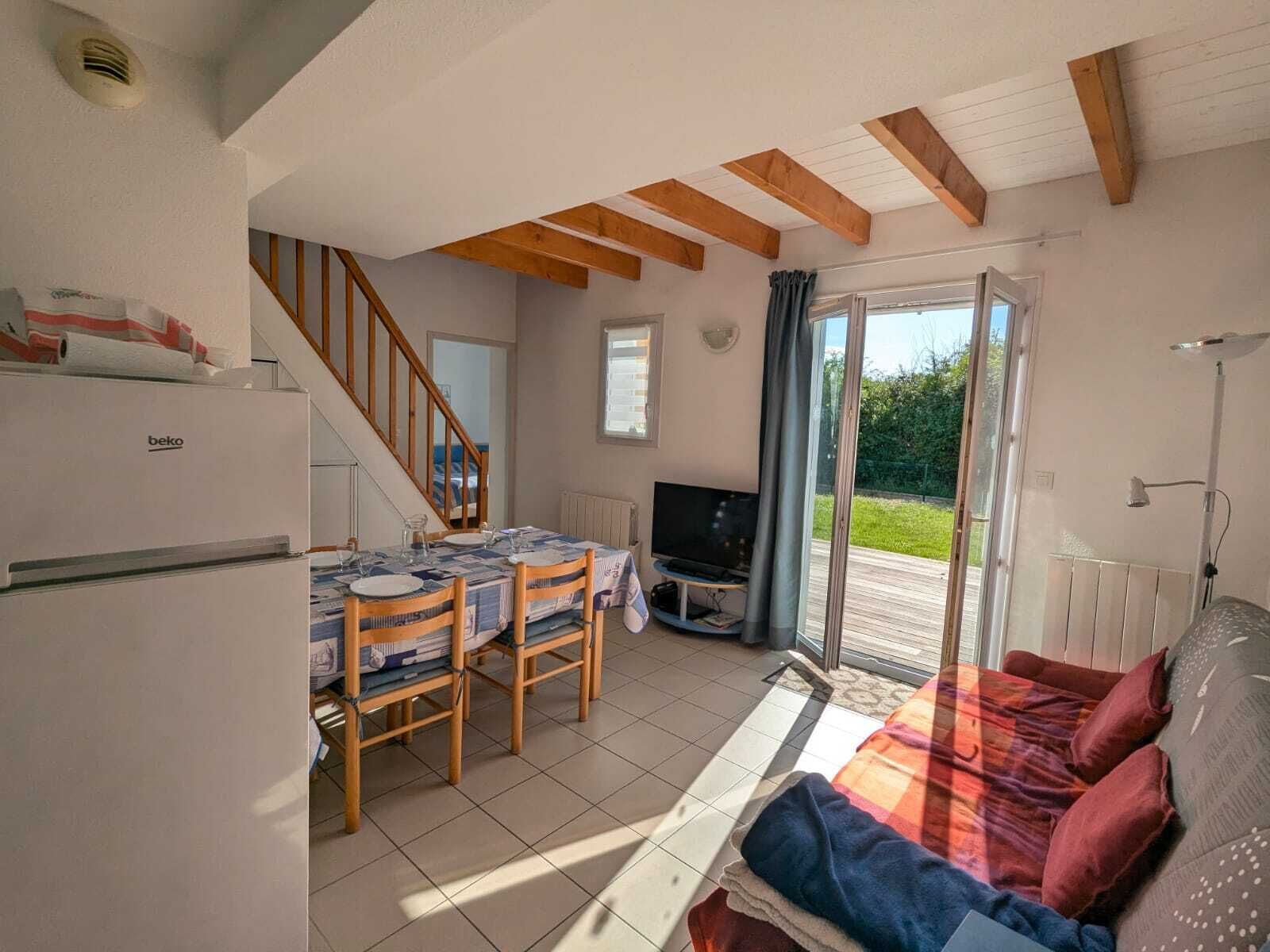 A compact living space with a dining area, a sofa, a TV, and a kitchenette.