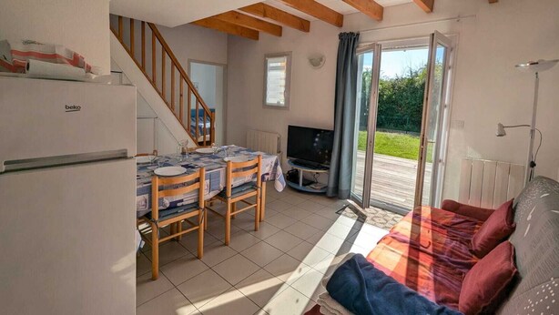 Un espacio habitable compacto con comedor, sofá, televisor y kitchenette.