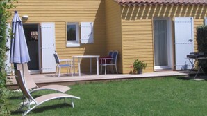 Un edificio amarillo con tejado de baldosas, un patio con sillas y una mesa, y un pequeño jardín.