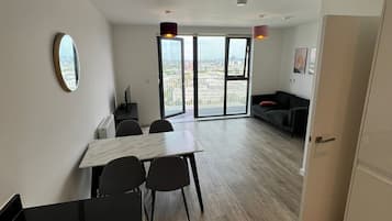 Un appartamento moderno con zona pranzo, divano e una grande finestra vista città.