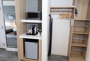 Eine kleine Küchenzeile mit Mikrowelle, Kaffeemaschine und Minikühlschrank.