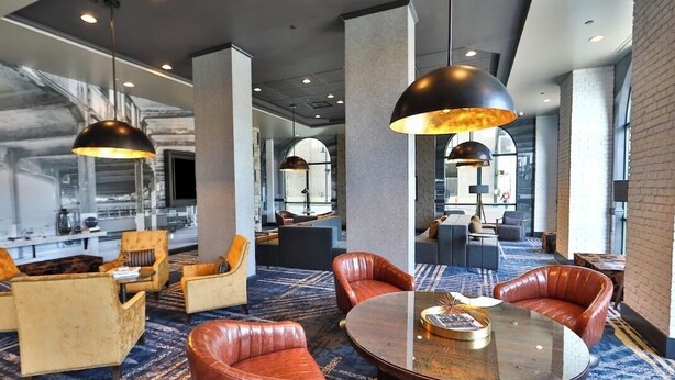 Eine moderne Hotelhalle mit Ledersofas, einem runden Tisch und Pendelleuchten.