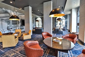 Eine moderne Hotelhalle mit Ledersofas, einem runden Tisch und Pendelleuchten.