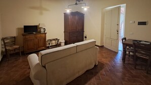 Un salon comprenant un canapé, un meuble en bois, une télévision et un coin repas avec une table et des chaises.