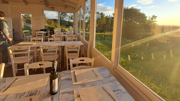 Un restaurant doté d’une terrasse, de grandes fenêtres et offrant une vue sur le paysage environnant.