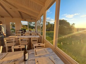 Un restaurant doté d’une terrasse, de grandes fenêtres et offrant une vue sur le paysage environnant.