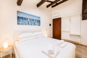 A bedroom with a large bed, a painting of sailboats, a wooden door, and a white wardrobe. - Naples Penthouse with Rooftop Castles Views (Naples)