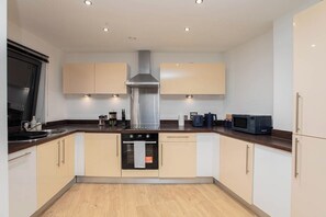 A modern kitchen with a central island, built-in oven, microwave, and stainless steel range hood. - Luxury 2Bed 2Bath City Centre Apt | Balcony View (Leeds)