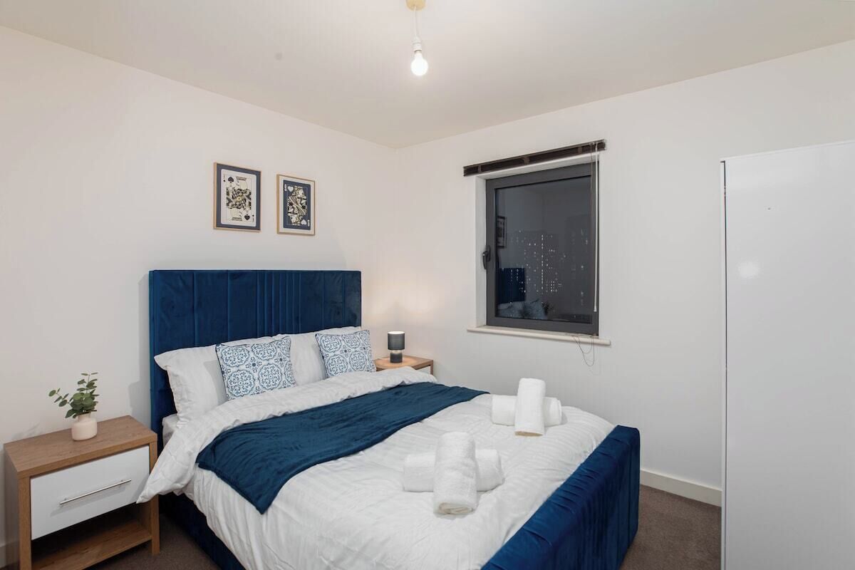 Un dormitorio con cama, mesitas de noche, una ventana y decoración en la pared.