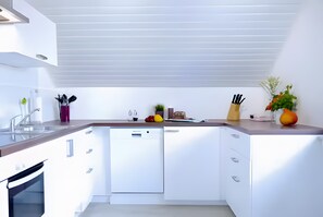 A modern kitchen with white cabinetry, a dishwasher, and a countertop with various kitchen items. - Apartment "For 4 Guests, 83 m²" with Wi-Fi (Zülpich)