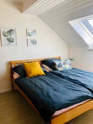 A bedroom with a sloped ceiling, a wooden bed, and two framed plant prints on the wall. - Apartment "For 4 Guests, 83 m²" with Wi-Fi (Zülpich)