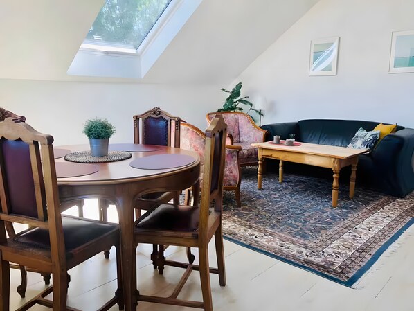 A dining area with a round table, chairs, a small plant, a sofa, and a rug. - Apartment "For 4 Guests, 83 m²" with Wi-Fi (Zülpich)