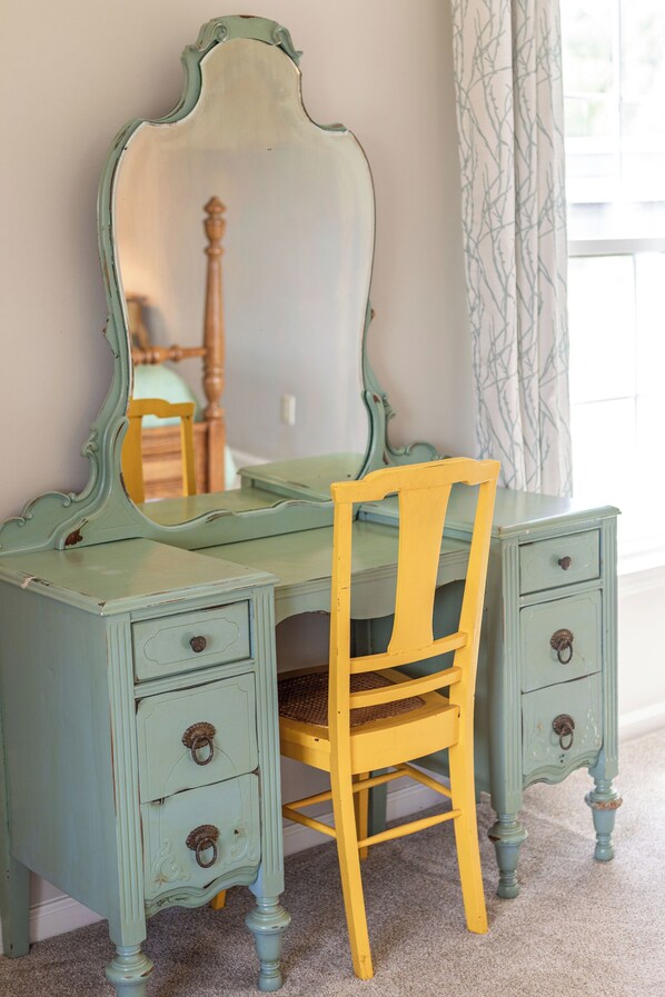 A vintage-style desk with a chair, drawers, and a mirror.