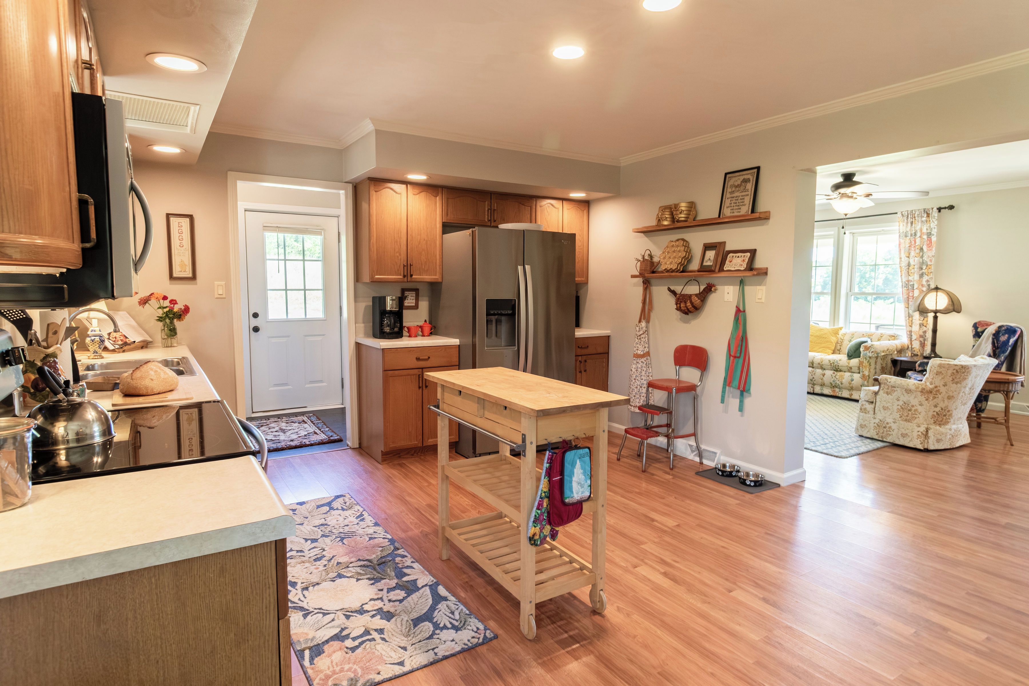 A modern kitchen with wooden cabinets, a refrigerator, and a dining area with a sofa and chairs.