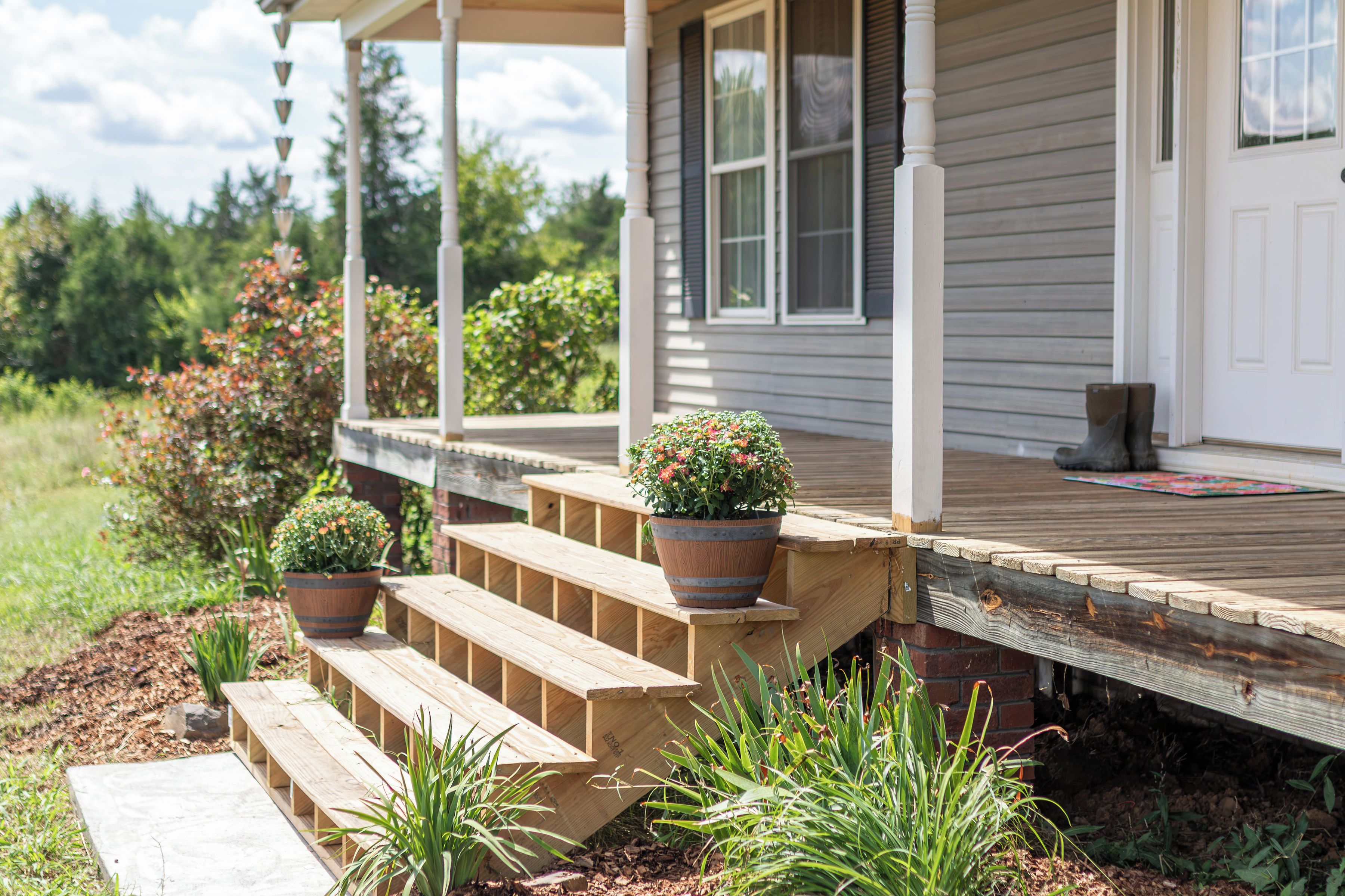 A wooden deck with steps leading to a house with a porch.