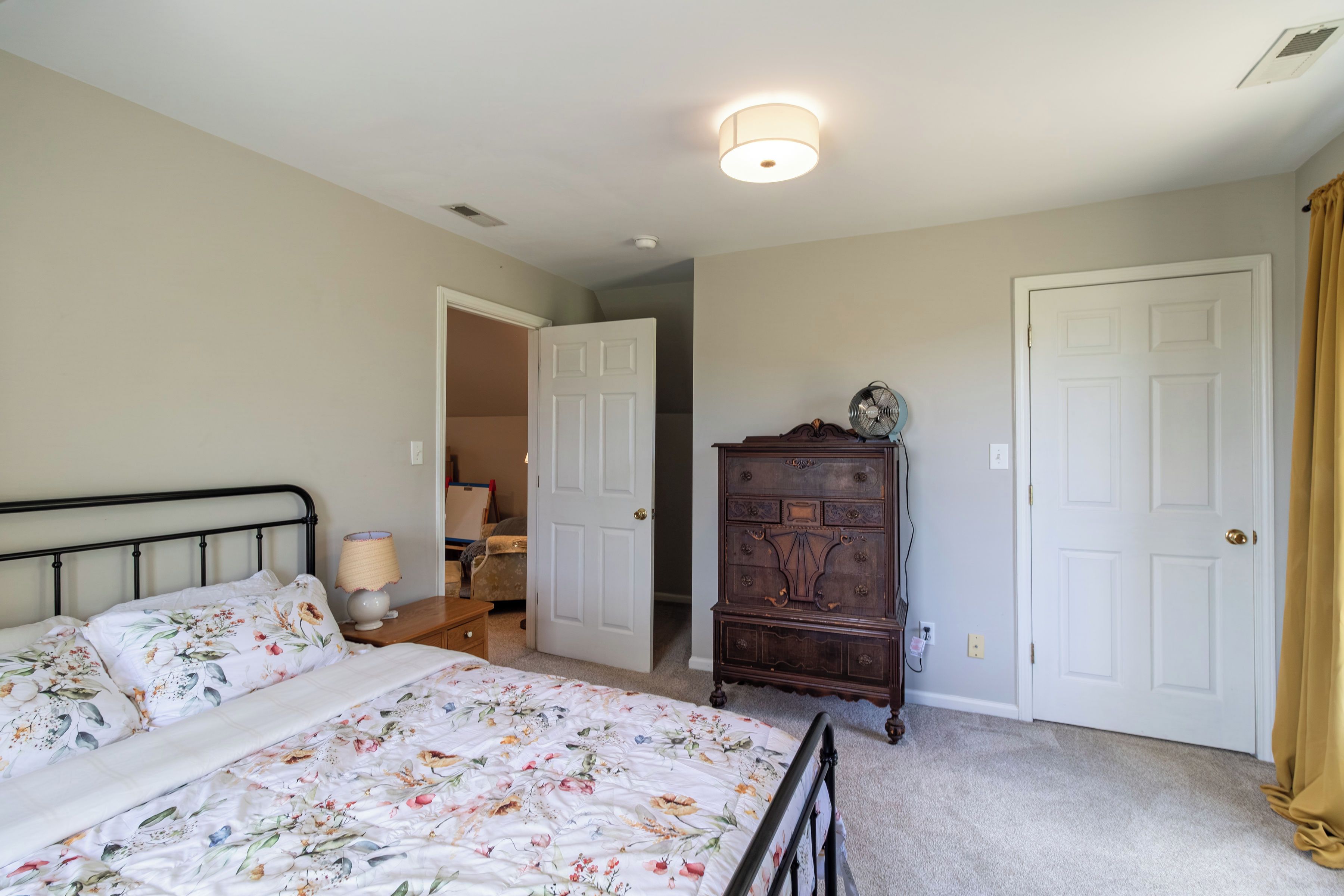 Un dormitorio con cama, cómoda y dos puertas.