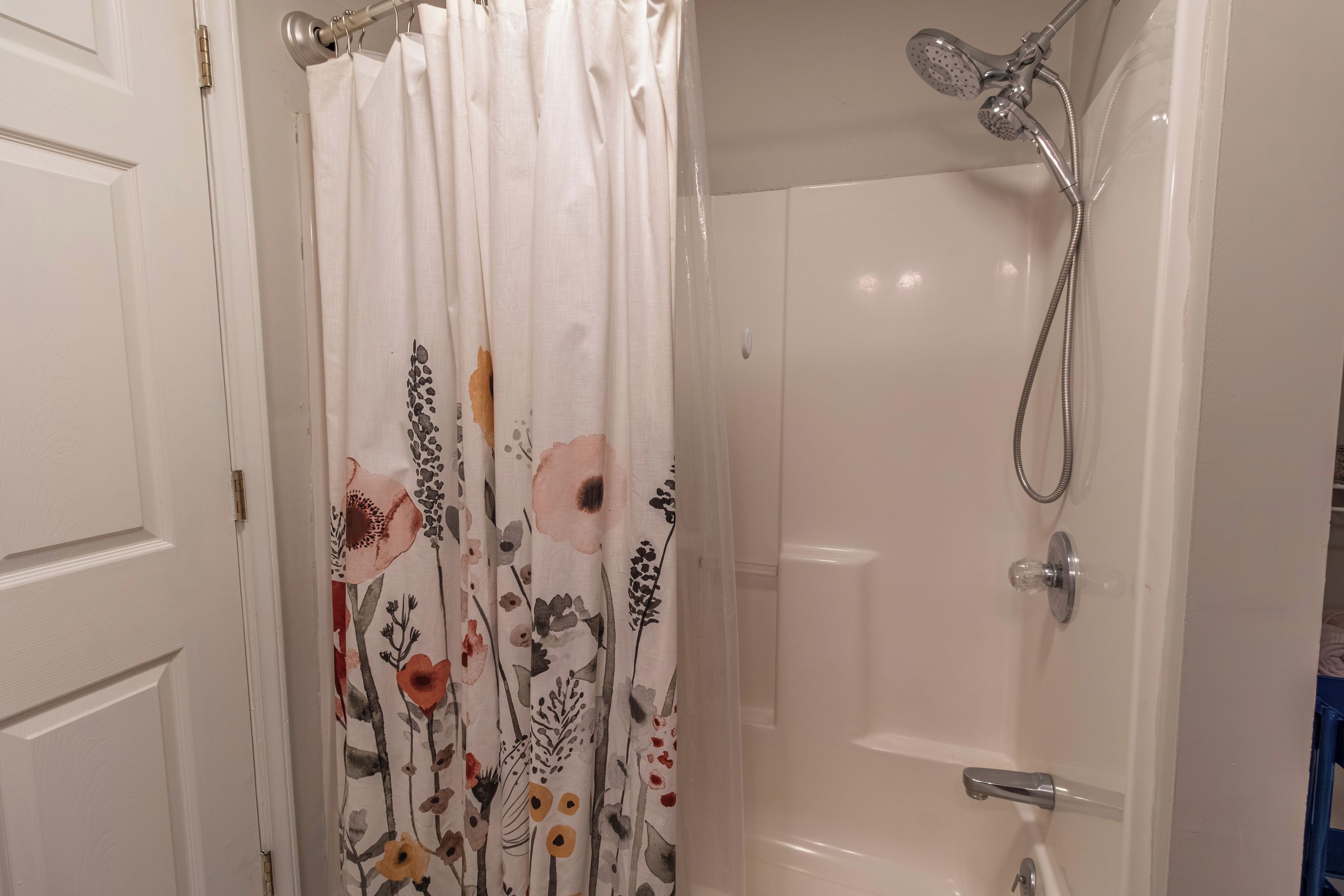 Kylpyhuone, jossa on suihku, wc ja kukkakuviollinen verho.