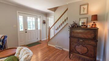 A spacious living room with hardwood flooring, a staircase, and a wooden dresser with decorative items.