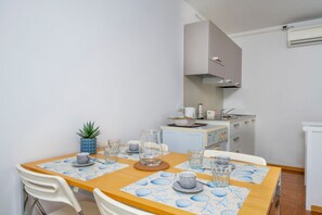 Eine kompakte Küche mit Essbereich, weißen Wänden und einer kleinen Kücheninsel mit Kaffeemaschine.