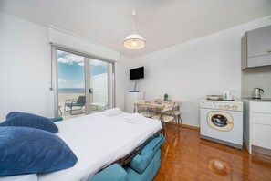 A compact room with a bed, a table, a chair, a washing machine, and a TV. - A comfortable 53-square-meter apartment, perfect for four people, located on the third floor (Scala A) of a building with an elevator (NOT suitable for people with disabilities) directly facing the seafront.The property is located in Lignano Sabbiadoro i (Lignano Sabbiadoro)