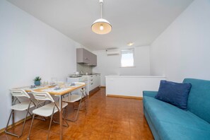 Ein kompakter Wohnraum mit Essbereich, Küchenzeile und einer Couch.