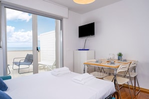 A hotel room with a bed, a TV, a dining table with chairs, and a view of the sea through a sliding door. - A comfortable 53-square-meter apartment, perfect for four people, located on the third floor (Scala A) of a building with an elevator (NOT suitable for people with disabilities) directly facing the seafront.The property is located in Lignano Sabbiadoro i (Lignano Sabbiadoro)