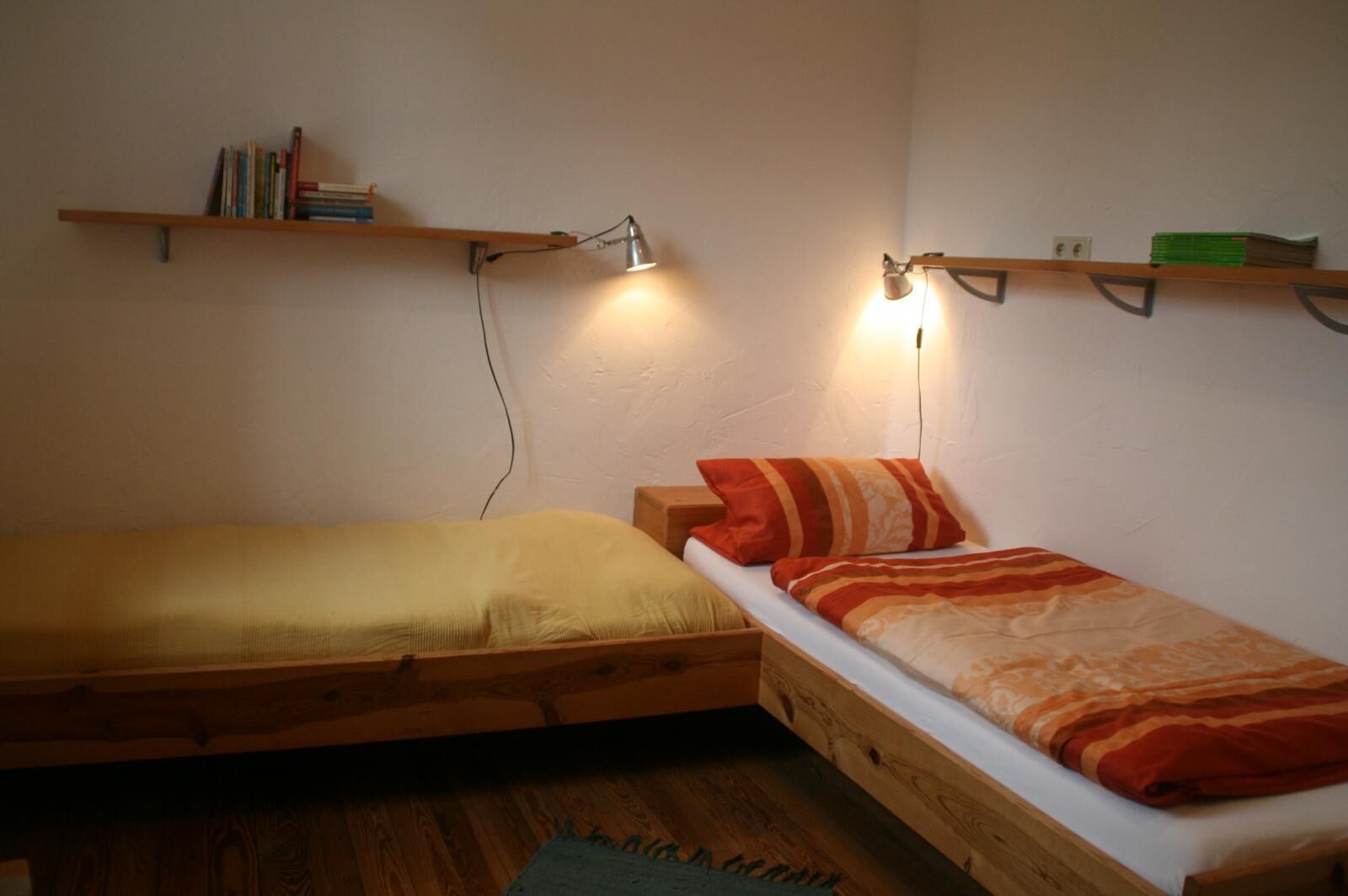 Two wooden bunk beds with attached shelves, a lamp, and a small rug.