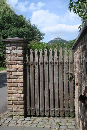 A wooden gate with vertical slats and a metal latch, set against a brick wall with a stone base.