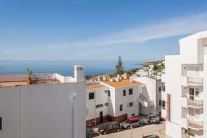 Ein Küstenwohngebiet mit weißen Häusern, blauem Himmel und Blick auf das Meer.