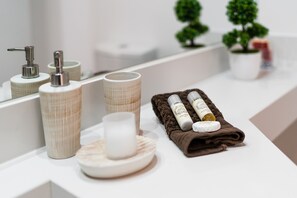 Ein Badezimmer-Waschtisch mit Spiegel, Handtuch und Pflegeprodukten.