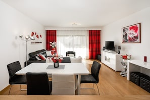 Ein modernes Wohnzimmer mit Essbereich, Fernseher und Kamin.