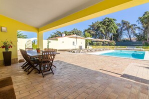 Un patio al aire libre con piscina, una mesa de comedor con sillas y una planta en maceta.