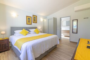 Ein Hotelzimmer mit Bett, Nachttisch, Lampe und Blick nach draußen.