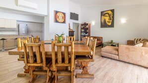 A spacious living area with a wooden dining table, a sofa, and a TV mounted on the wall. - Villa Dean Private Pool For Families AC WI- (Lagos)