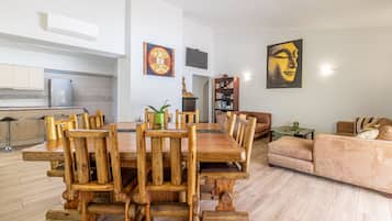 Un amplio salón con una mesa de comedor de madera, un sofá y un televisor montado en la pared.